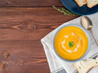 Dietary vegetarian pupmkin cream soup puree,  on dark brown wooden table, top view, copy space, close up.