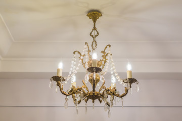vintage chandelier hanging under white ceiling with stucco moldings