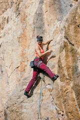 Woman climbs a yellow rock with a rope, lead, side view