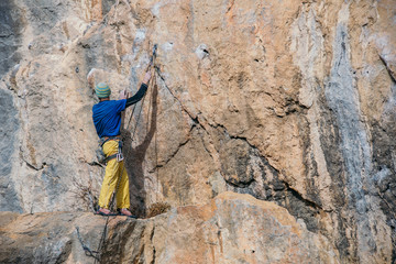 Man climbs a yellow rock with a rope, lead