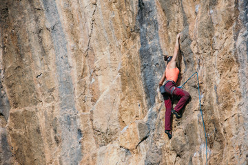 Woman climbs a yellow rock with a rope, lead, side view