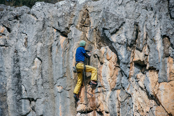 Man climbs a yellow rock with a rope, lead