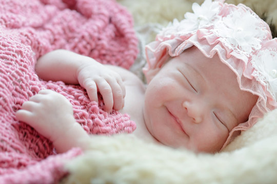 Newborn baby girl smiling in a dream ,Newborn baby girl is sleeping on fur blanket