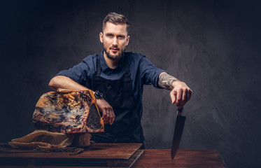 Professional butcher holds a knife standing with raw smoked meat