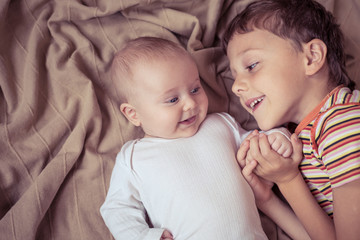little boy playing with newborn on the bed © altanaka
