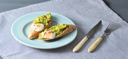 Breakfast of baguette, eggs and crushed avocado
