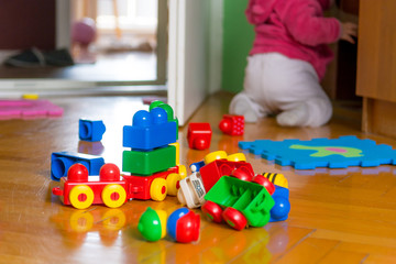 Baby playing with colorful bricks on wooden floor.