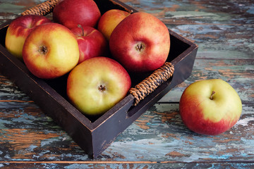 Red and yellow apples in a box on a wooden table