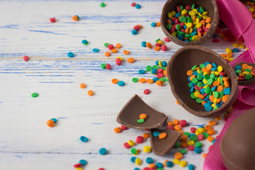 Obraz premium Easter Chocolate Eggs, Pink Tape and Multicolored Sweets on the Old White Wooden Background. Easter concept