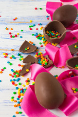 Easter Chocolate Eggs, Pink Tape and Easter Multicolored Sweets on the Old White Wooden Background