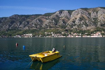 Fototapeta na wymiar Tiny Yellow Boat in Kotor, Bay of Kotor, Montenegro