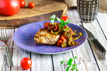 Pork cutlet with vegetable sauce on a violet plate