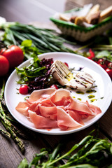Appetizing dish of meat and cheese with greens on a wooden background