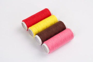 Four bobbins of new colorful threads on white background