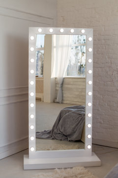 Mirror whith white frame and light bulbs in interior flat. Close up