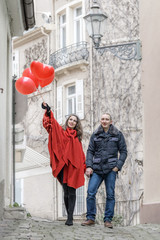Obraz na płótnie Canvas love story. A young man and a young woman with red accessories are walking in the city