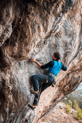 Men climbs a rock with a rope, lead, in cold weather. Hard pitches. Chitdibi, Turkey