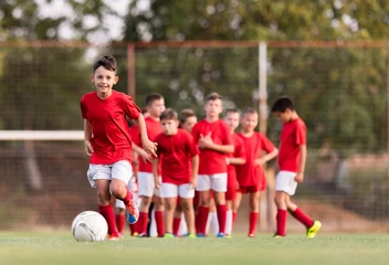 Deurstickers Boy kicking football on the sports field © Dusan Kostic