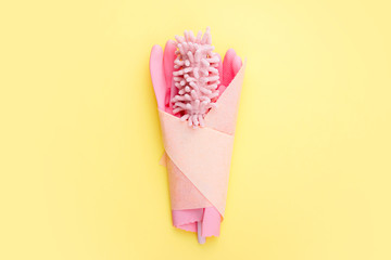 concept international women's day, a bouquet of tools for cleaning on a yellow bright background, pink gloves and a soft dust brush