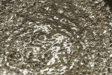 Boiling water, close up of escaping bubbles of steam in boiling water. Abstract Backgrounds.