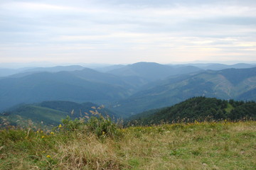 The landscape of the Ukrainian Carpathians against the background of the evening cloudy sky from the height of the highest peak of the mountain range.