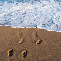 Sea ocean beach. Blue water with foam and footprints