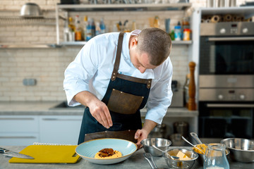 food cooking, profession and people concept - male chef cook serving plate of polenta and veal...