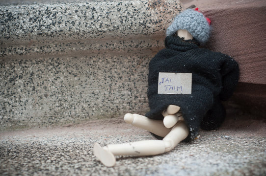 closeup of wooden puppet in the street with help sign (text in french) traduction of I am hungry - concept poverty