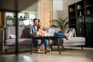 Surface level view of couple watching laptop in living room with modern interior