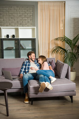 Young couple lying on couch in modern living room