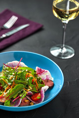 Spicy beef slices meat salad with tomatoes, parsley, radish and salad leaves spinach on black texture background table