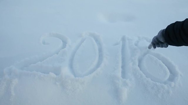woman's hand writes 2018 sign on the white snow