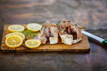 the process of cooking fish, two fresh raw tasty pieces of fish with lemon slices and parsley on wooden Board