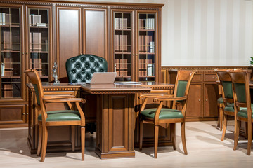Interior of office room with chairs and laptop on wooden table in classic design