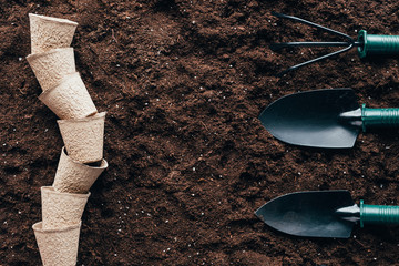 top view of empty flower pots and small gardening tools on soil