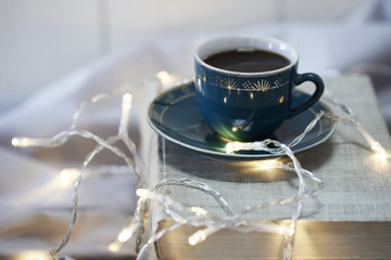 Cup of coffee on book with christmas lights