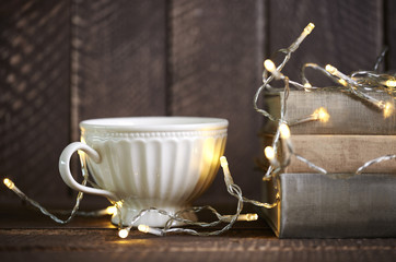 Obraz na płótnie Canvas Cup of coffee next to book and christmas lights