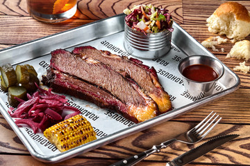 Smoked barbecue beef brisket with sauce, corn, marinated cucumber and onions