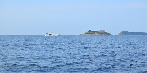 Fototapeta premium Tourist boat sailing on a sea and passing by an island