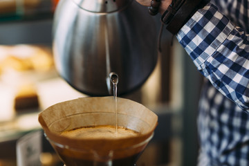Barista pouring water on coffee in a chemex machine