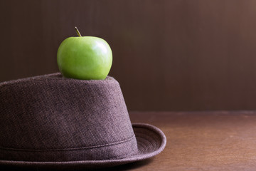 Hat and green apples in the room with the light and shadow is beautiful.