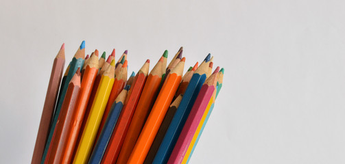 Colored pencils in jar on a pale background close up