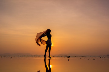Fototapeta na wymiar Silhouette of a Beautiful Woman at the beach in Thailand at sunset