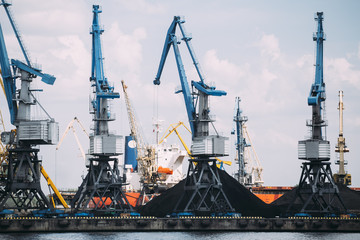 Cranes in industrial port with coal in the background