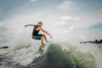 Active wakesurf rider jumping on the waves of the river
