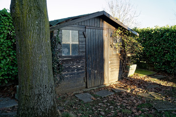 Old desolate barn with dirty vintage window, cute small house on back yard