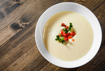 Creamy fish soup with salmon, potatoes, onions, cauliflower and carrots on a wooden background