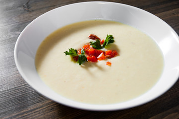 Creamy fish soup with salmon, potatoes, onions, cauliflower and carrots on a wooden background