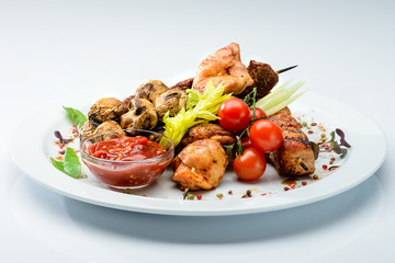 Appetizing dish with meat, mushrooms, tomatoes and salad at the white plate, close-up. For menu design