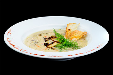 Tasty mushroom cream soup with parsley and spices in a white plate served with toast bread over dark background. Autumn menu in an Italian restaurant
